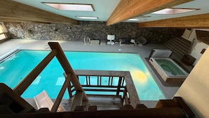 A pool area with a stone wall, wooden deck, and a hot tub. - Eagle's Bluff Estate on Flathead Lake near Glacier National Park (Polson)