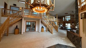 A spacious interior with a central staircase, wooden railings, and a decorative light fixture. - Eagle's Bluff Estate on Flathead Lake near Glacier National Park (Polson)