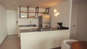 Eine moderne Küche mit einer zentralen Kochinsel, einem Kühlschrank, einer Kaffeemaschine und einem Regal mit Dekoration.