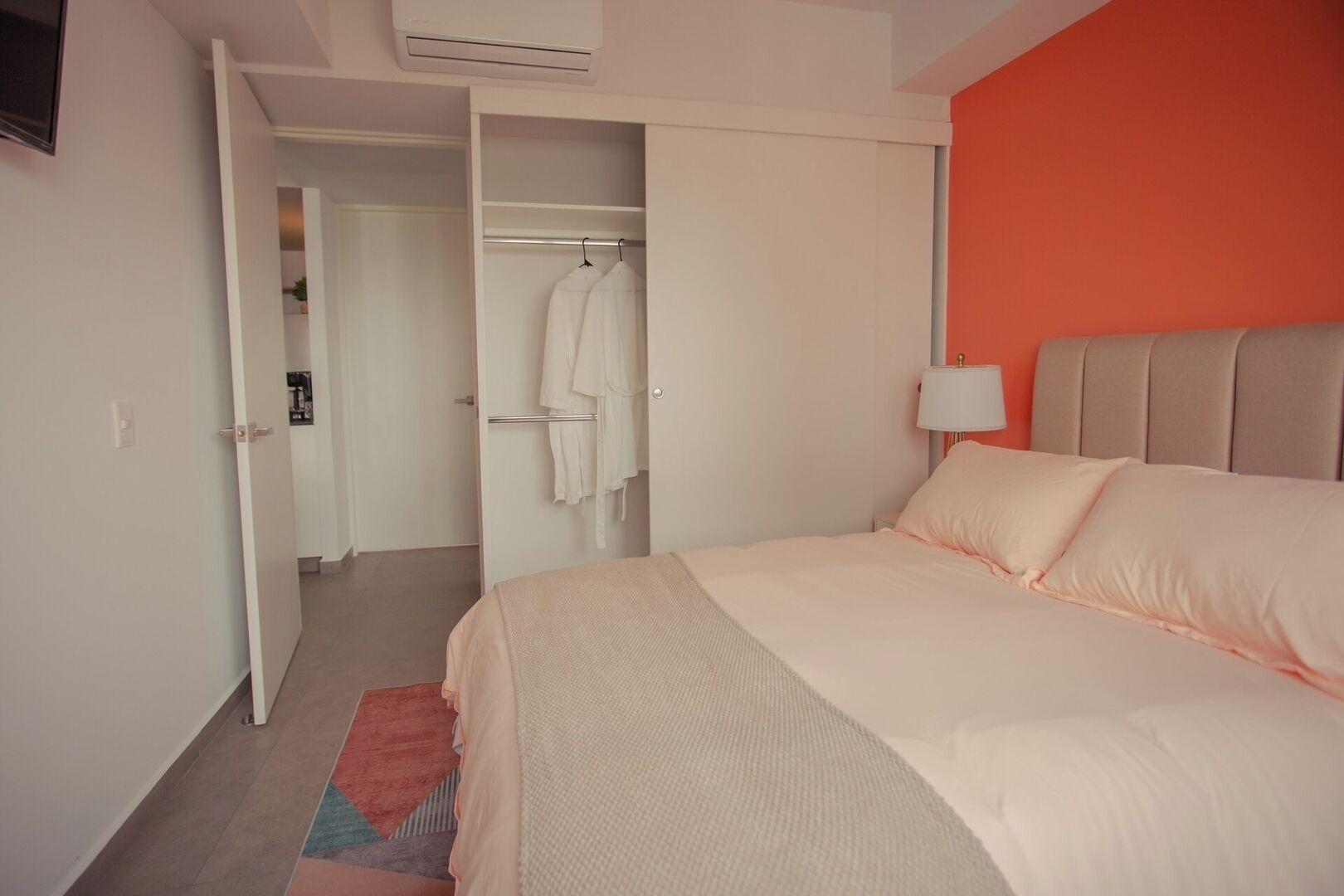 A hotel room with a bed, a wardrobe, and a walk-in closet.