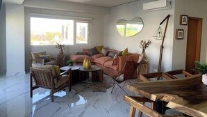 Ein modernes Wohnzimmer mit einer Couch, Sesseln, einem Couchtisch und einem Holzessttisch.