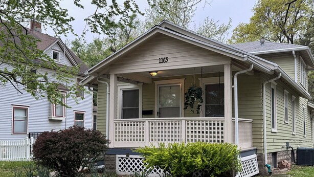 A single-story house with a front porch, a mailbox, and a number '1165' on the front.