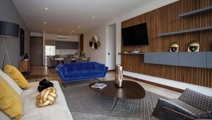 Ein modernes Wohnzimmer mit einem blauen Sofa, einem Couchtisch und einem gemusterten Teppich.