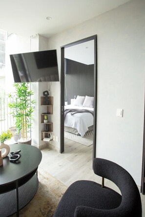 Een moderne slaapkamer met een bed, een televisie, een stoel en een plant.