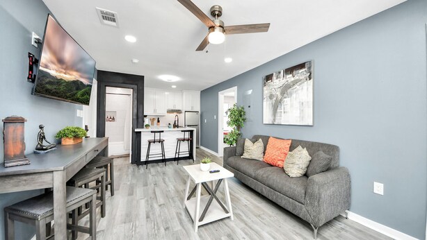 A modern living room with a gray sofa, a coffee table, a TV, and a ceiling fan. - Arbor Flats #8 in the Heart of Houston (Houston)