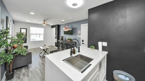 A modern kitchen with a central island, a dining area, and a living space with a ceiling fan. - Arbor Flats #8 in the Heart of Houston (Houston)