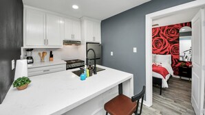 A modern kitchen with white cabinets, a central island, and a black faucet. - Arbor Flats #8 in the Heart of Houston (Houston)