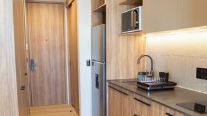 Eine moderne Küche mit Holzschränken, einem Edelstahlkühlschrank und einer eingebauten Mikrowelle.