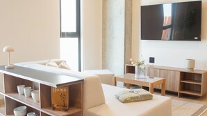 Ein modernes Wohnzimmer mit einer Couch, einem Couchtisch, einem an der Wand montierten Fernseher und einem Bücherregal.