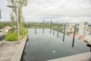 A rooftop pool with a city view, surrounded by greenery and modern buildings. - Mr. W | Incredible loft in Livify (Zapopan)
