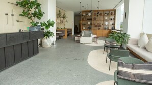 Um hall moderno com balcão de recepção, área de estar e parede decorativa.