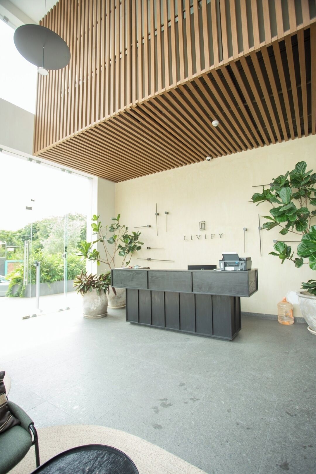 Un mostrador de recepción de diseño moderno, techo con listones de madera y plantas en macetas.
