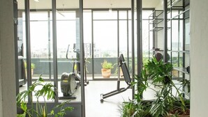 Um espaço de escritório moderno com grandes janelas, uma esteira e plantas em vasos.