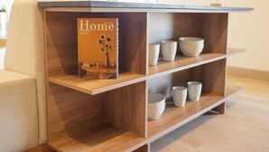 En hylla i trä med en bok som heter ”Inredning för hemmet” och flera vita skålar.