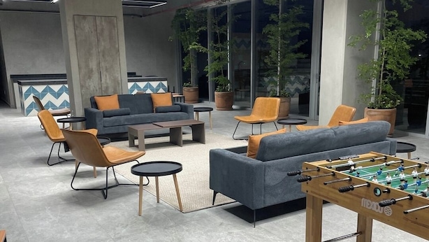 Un'area lounge moderna con divani, poltrone, un tavolo da calcio e piante in vaso.