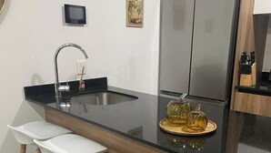 Una cucina moderna con un piano di lavoro nero, elettrodomestici in acciaio inossidabile e sgabelli di legno.