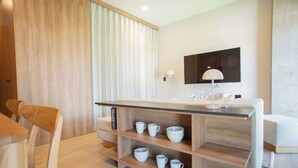 A modern kitchen with a wooden countertop, white cabinets, and a built-in shelf with cups and bowls. - Mr W | 1BR Margot Loft Modern City Tower (Guadalajara)