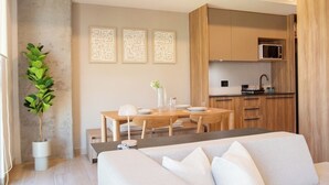 A modern living room with a sofa, a dining table, and a kitchen area in the background. - Mr W | 1BR Margot Loft Modern City Tower (Guadalajara)