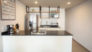 Une cuisine moderne dotée d’un îlot central, d’un réfrigérateur, d’une machine à café et d’un évier.