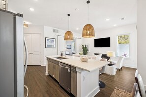 Una cocina moderna con una isla central, electrodomésticos de acero inoxidable e iluminación colgante.