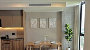 Ein modernes Wohnzimmer mit einer Couch, einem Esstisch und einer dahinterliegenden Küche.