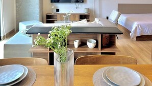 Ein modernes Hotelzimmer mit Essbereich, einem Flachbildfernseher, einem Bett und einem Nachttisch.