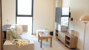 Un salon moderne avec un canapé, une table basse, un téléviseur et une lampe.