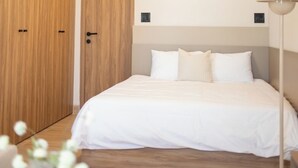 Une chambre à coucher comprenant un lit, une armoire en bois, deux œuvres d’art encadrées accrochées au mur, une lampe de chevet et un vase avec des fleurs.