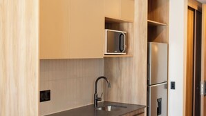 Une cuisine moderne avec des meubles en bois, un réfrigérateur en acier inoxydable et un four à micro-ondes encastré.
