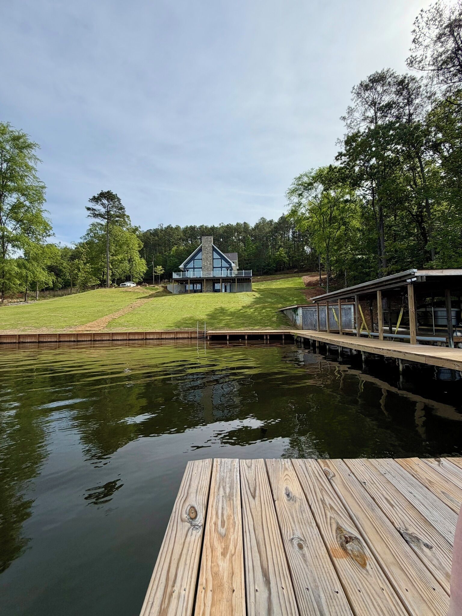 Une propriété au bord du lac, dotée d’un quai, d’une maison avec une cheminée en pierre et d’un espace abrité.