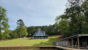 A lakeside property with a dock, a house with a stone chimney, and a covered area. - Cozy Ridge Retreat: A Spacious 6-bed waterfront house on beautiful Lake Mitchell (Rockford)