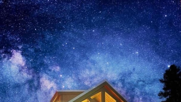 A cabin with a starry night sky, a wooden exterior, and a lit porch. - Luxury Cabin with Mountain View 7A (Williams)