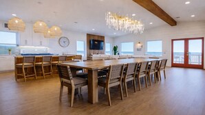 Una cocina amplia con suelo de madera, una gran mesa de comedor y luces colgantes.
