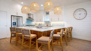 Cocina moderna con una isla central, sillas de madera y lámparas colgantes.