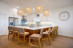 A modern kitchen with a central island, wooden chairs, and hanging pendant lights. - OTB1224 On the Beach, Beautiful Views (Port Aransas)