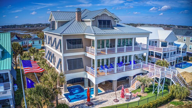 A multi-story building with balconies, a swimming pool, and a flag.