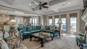 A spacious living room with a sectional sofa, a coffee table, and a ceiling fan.
