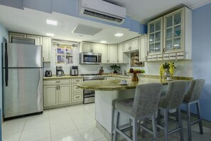 A modern kitchen with a central island, stainless steel appliances, and light-colored cabinetry. - 1BR1BA Condo @Wacamaya Condos~Pool, BBQ & Balcony (Noord)