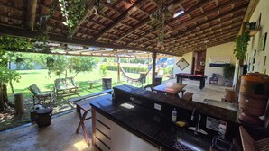 Uma área de cozinha externa com churrasqueira, mesa de jantar e cadeiras.