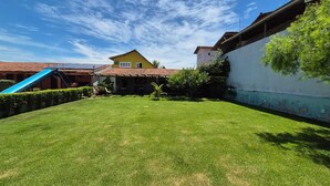 Quintal com gramado, escorrega azul e casa com telhado vermelho.