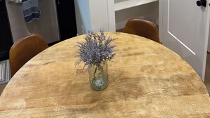 A dining area with a round table, a vase with flowers, a kitchen with cabinets, and a white door. - 2-bedroom apartment in Utah County (American Fork)