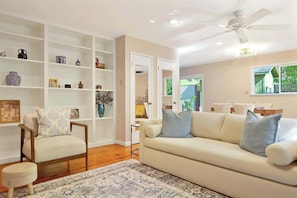 A living room with a sofa, armchairs, a coffee table, and a bookshelf. - Wine Country Creekside Cottage Bridge & Day Studio (Kenwood)