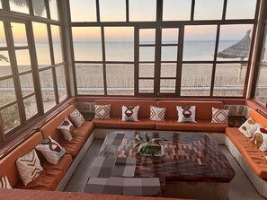 Una habitación con un gran ventanal con vista a la playa, un conjunto de sofás y una mesa de centro.