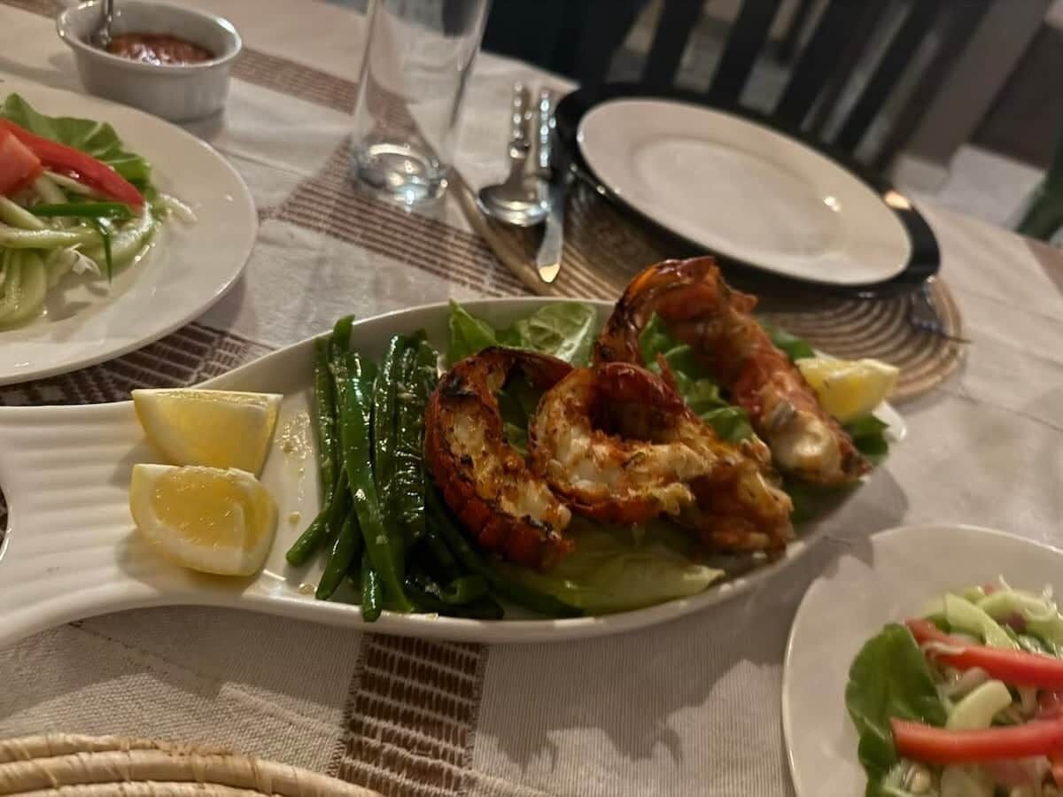 A dining table with plates of food, including grilled shrimp and vegetables, and a glass of water.