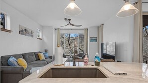 Una cocina moderna con una isla central, horno empotrado y un amplio ventanal.