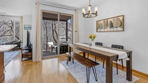 Un comedor con una mesa de madera, bancos y una araña.