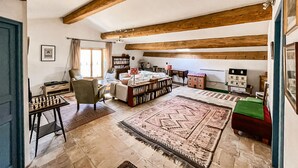 A spacious living room with exposed wooden beams, a bookshelf, a sofa, a coffee table, and a patterned rug. - Beautiful home in Alignan-Du-Vent (Alignan-Du-Vent)
