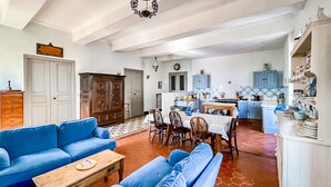 A living room with a blue sofa set, a wooden coffee table, and a dining area with a table and chairs. - Beautiful home in Alignan-Du-Vent (Alignan-Du-Vent)