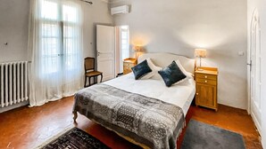 A bedroom with a bed, two bedside tables, a chair, a radiator, and a window with curtains. - Beautiful home in Alignan-Du-Vent (Alignan-Du-Vent)