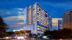 A high-rise hotel building with illuminated windows, a prominent sign, and a modern glass facade. - Muwang Hotel Dalian (Dalian)